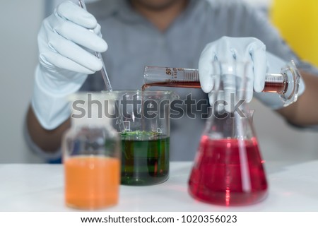 Close up open glass conical flasks standing in line with colorful liquids inside, chemical substances, solutions, standing on the white table in the laboratory . Chemical , industry ,Hazards concept .