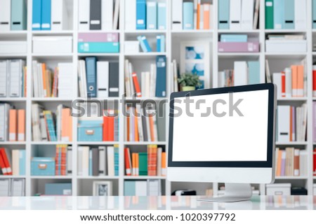 Professional creative workspace with computer on a white desktop and colorful folders on the shelves