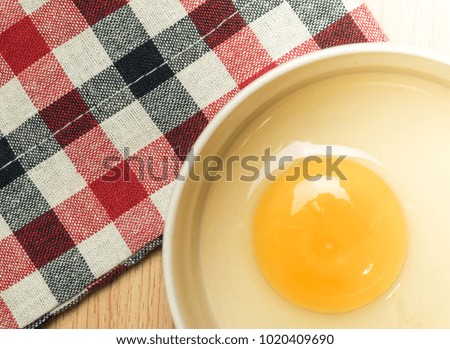Egg in a bowl beside Red checkered pattern Table Cloth