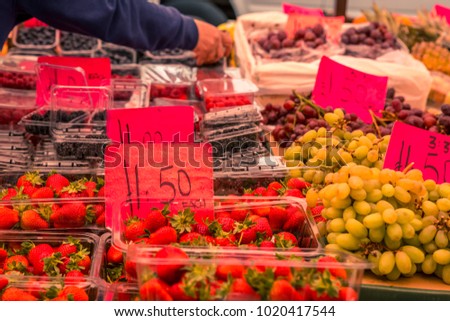 Different types of colorful fruits, for sale at Portobello Road market in London, England, United Kingdom. Strawberries, blackberries and grapes with signs of hand written prices.