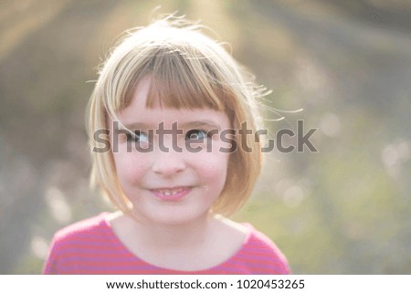 Little girl with blond hair and brown eyes radiates happiness and light in the sunshine.