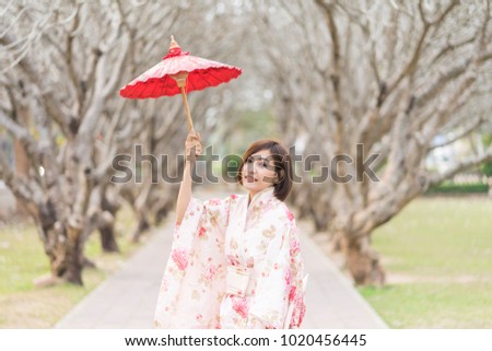 portrait of asian woman wearing kimono holding traditional red umbrella