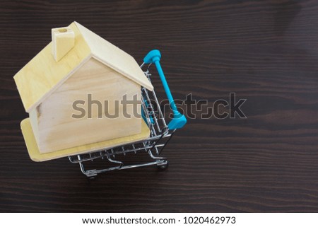 miniature wooden house in mini shopping cart on wood table background.
Image for property real estate investment concept. 
Homes for sale in old market.
(selective focus )