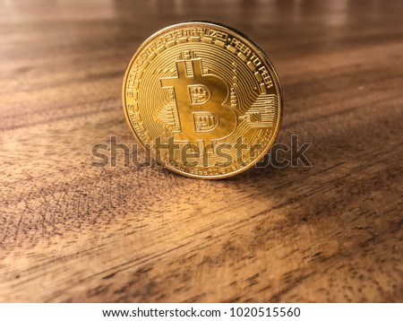 Bitcoin. Physical bit coin. Digital currency. Cryptocurrency. Golden coin with bitcoin symbol isolated on wooden background