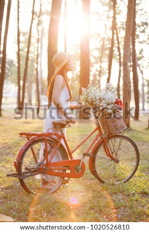 Photo with vintage toning ,young female in a hat with a bike in pine forest.