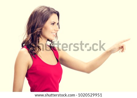 Profile view of smiling beautiful young woman in casual smart red clothing, showing copyspace, visual imaginary or something, or pressing virtual button.
