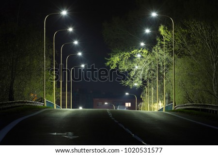 city road at night with LED streetlights, central view Royalty-Free Stock Photo #1020531577