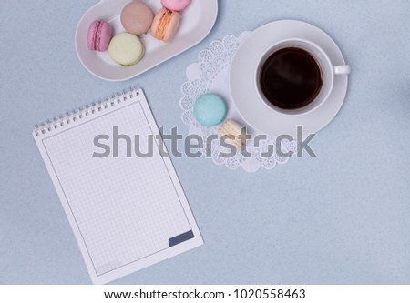 Empty notepad, coffee and colorful macaron on pink pastel desk top view. Cozy morning breakfast. Fashion flat lay.