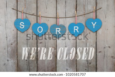 blue wooden hearts with text sorry we are closed, on old scaffolding wooden backdrop, with copy space