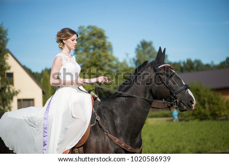  Young woman wearing a white dress riding horse