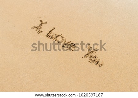Word of I love you written with letters on sand.