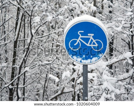 Cycle track, bike path road sign on snow-covered forest background; average plan