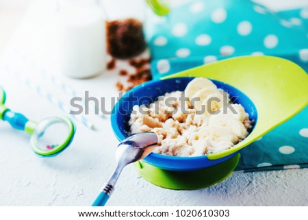 food, baby instant porridge with cereals, oatmeal, rice, semolina or corn, with banana and milk in a blue bowl on a white background