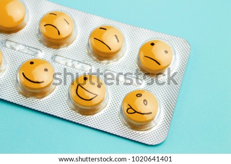 Orange pills and funny faces in a blister on a blue background. The concept of antidepressants and healing