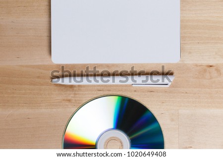 mock up of blank printable compact cd or dvd disc, pen and white notebook on wooden office table