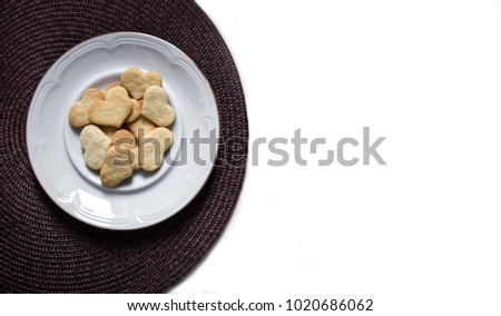 on a white background on a dark napkin is a plate with cookies in the form of a heart