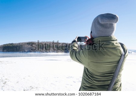 Girl photographing winter scenery with her phone