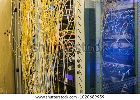 Messy Internet wires are tangled together in the server-side date center. Powerful computer equipment works in server cabinets.