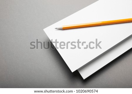 Two invitations on a gray background with a pencil.