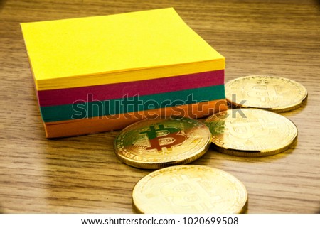 Golden bitcoins on wooden desk, cryptocurrency background with paper notes.