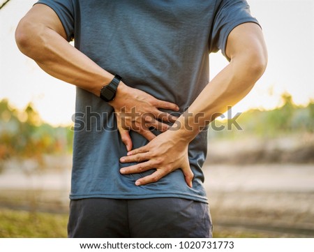 Back pain, close up young man has injury during outdoor exercise Royalty-Free Stock Photo #1020731773