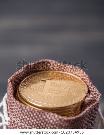 Bitcoin in small brown pouch over wooden table top