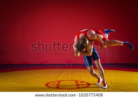 Two greco-roman  wrestlers in red and blue uniform wrestling   on a yellow wrestling carpet in the gym Royalty-Free Stock Photo #1020775408