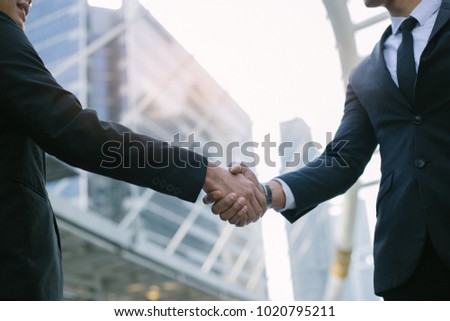 Businessman in suit handshake together for successful in city and walking people background.