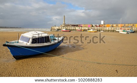 The beach at low tide with mooring boats and Margate Harbor Arm in the background, Margate, Kent, UK Royalty-Free Stock Photo #1020888283