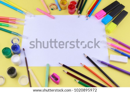 paper with colored crayons, brush, pencils and paints on yellow background. Top view . Flat lay image.Working desk table concept.