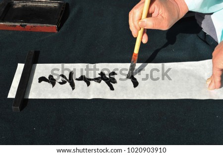 A calligrapher in the middle of writing in Chinese. The Chinese script in the picture is Ipchun (Onset of spring).