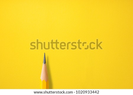 Minimalist template by top view close up macro photo of wooden yellow pencil put on yellow paper with copy space. Flash light Make a difference between yellow pencil and paper by shadow. Royalty-Free Stock Photo #1020933442