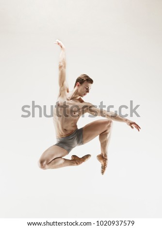 The male athletic ballet dancer performing dance isolated on white background. Studio shot. Ballet concept. Fit young man. Caucasian model