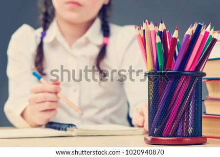 Front focus picture of smiling cute little girl writing something on the grey background