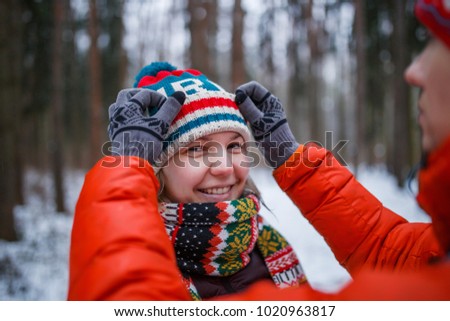 Photo of man adjusting woman's hat in winter forest