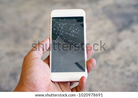 Businessman holding a crack smartphone. Shallow DOF