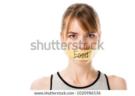 woman with stiker with striked through word food covering mouth isolated on white Royalty-Free Stock Photo #1020986536