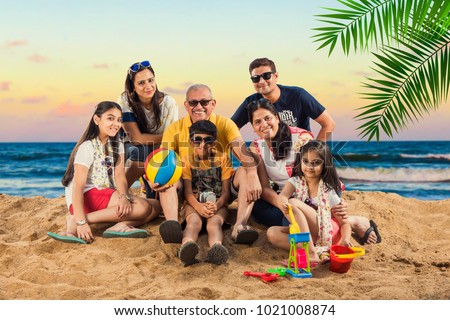 portrait of Indian family enjoying vacation at beach with suitcase, beach ball, clicking selfie picture
