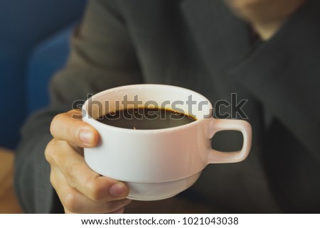 Businesswoman holding a cup of coffee in the coffee shop.