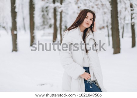 A beautiful and fashoin woman in white warm clothing walking in snowy weather.