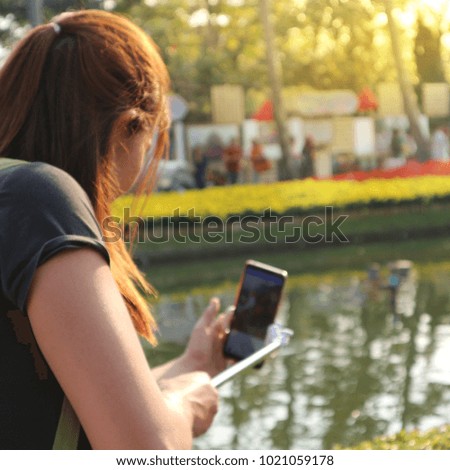 Girl with smartphone and monopod taking selfie,soft focus