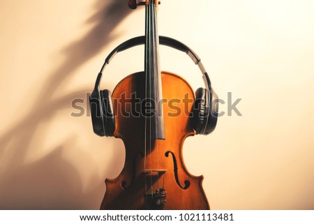 Old violin and wireless earphones. A background map of the concept of music.