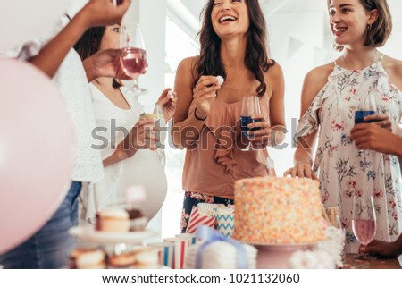 Group of women at a baby shower enjoying food and drink. Pregnant woman celebrating baby shower with female friends at home. Royalty-Free Stock Photo #1021132060