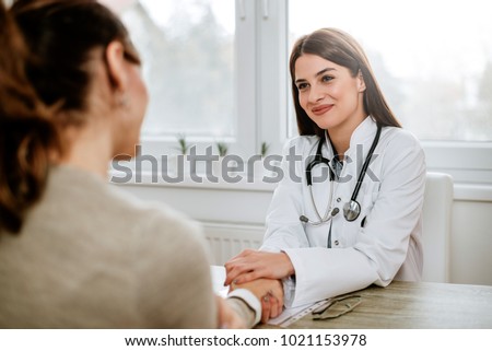 Friendly female doctor holding female patient's hand for encouragement and empathy. Royalty-Free Stock Photo #1021153978