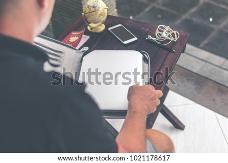 Man with luxury snakeskin python laptop case on a table outside the asian garden. Men fashion concept. Laptop bag.