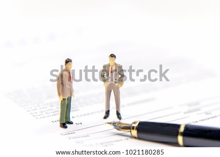 Businessman partners miniature people figure sign contract and agreement standing on the Agreement Contract paper.  Success and Business Concept. select focus
