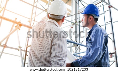 Senior and junior engineers discussing work together in site project, senior man pointing at structure for building. Concept engineer, technician