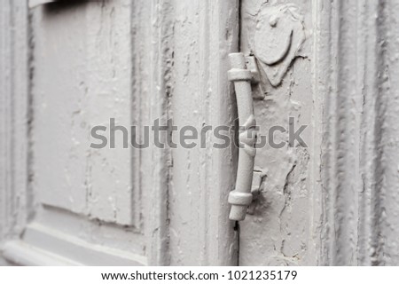 Close-up keyholes with curtains and a handle on the gray many times painted cracked double-barreled wooden vintage door of the last century with a post slit.