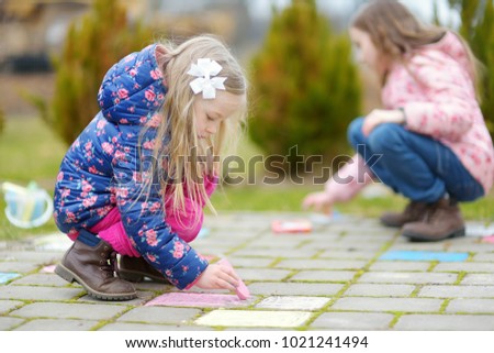 Two happy children drawing with colorful chalks on a sidewalk. Summer activity for small kids. Creative leisure for family.