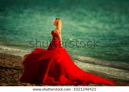 A woman in a red dress on the beach. Maritime vacation. Journey to the sea